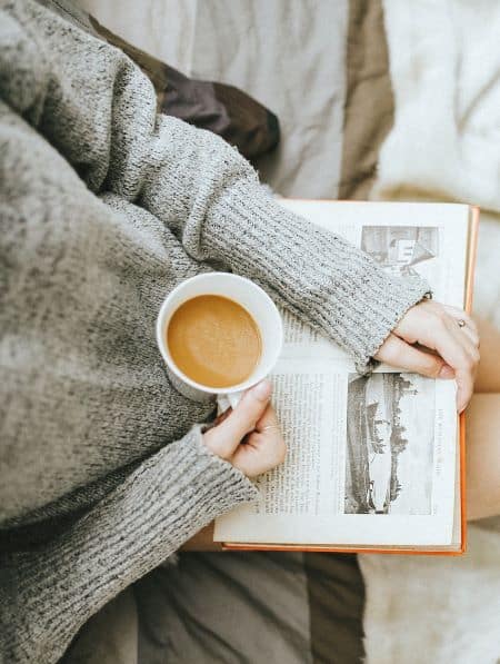 femme lisant un livre en prenant un café