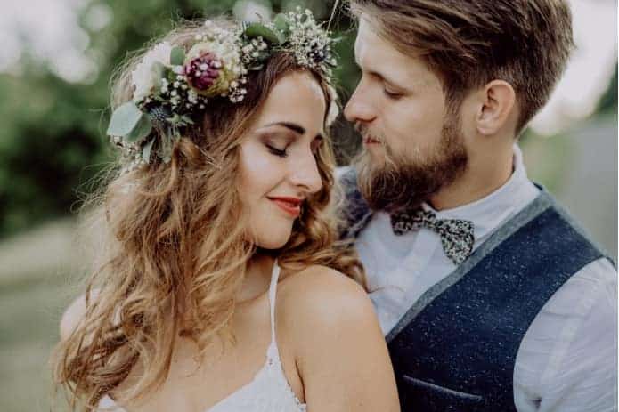 jeune femme avec couronne de fleur et homme en costume lors d'un mariage à thème