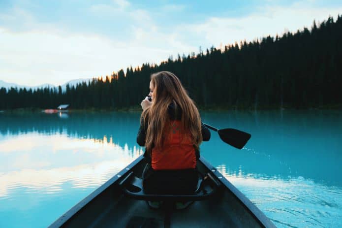femme de dos sur une pirogue dans un lac à banff