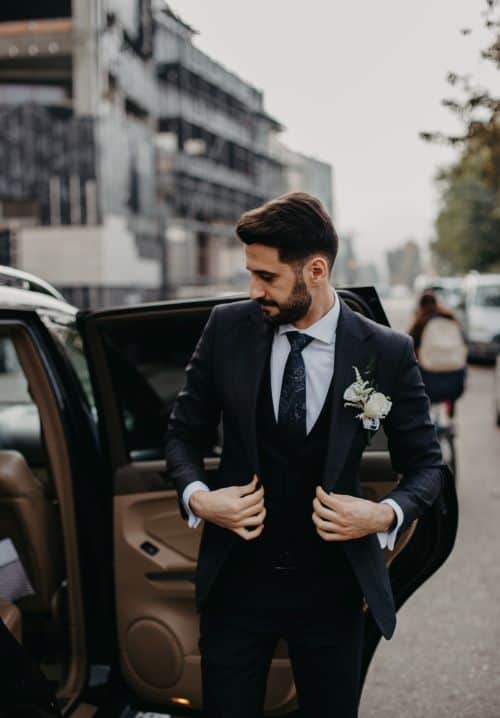 homme portant un costume de mariage noir devant voiture