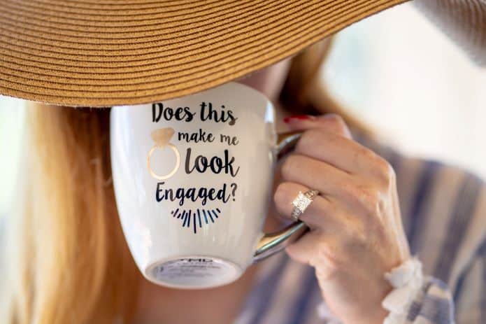 annonce de mariage sur un mug tenue par une femme avec chapeau et bague de fiançailles