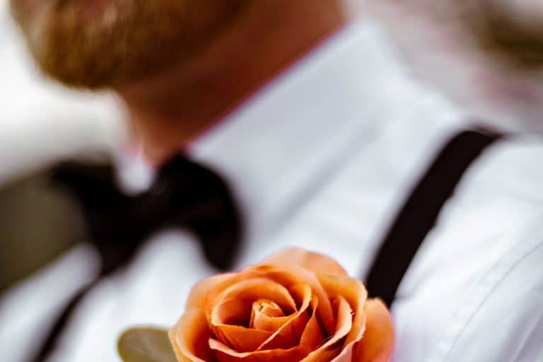 homme portant un smoking pour son mariage avec une rose orange