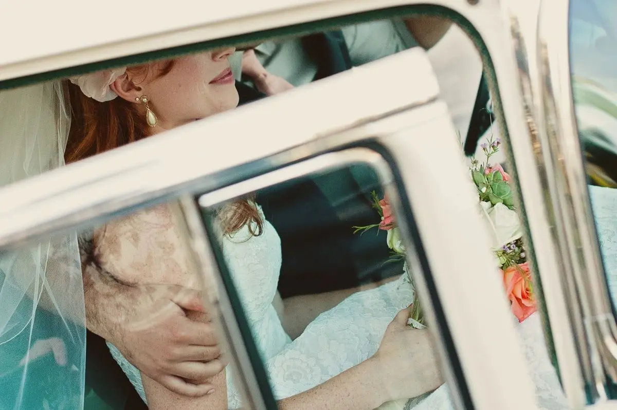 père de la mariée en costume serrant sa fille dans la voiture de mariage